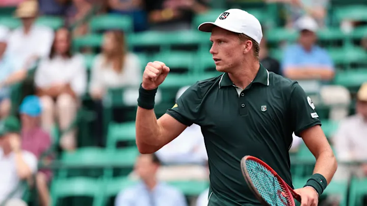 Il tennista statunitense Jenson Brooksby in completo verde scuro e cappellino da sole bianco esulta per un punto ottenuto durante il torneo ATP 250 di Houston in cui conquisterà il suo primo titolo in carriera